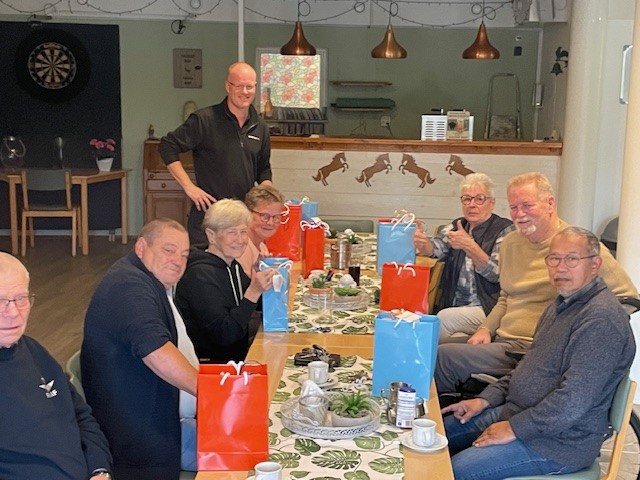 Vrijwilligers lachend op de foto in een ontmoetingsruimte