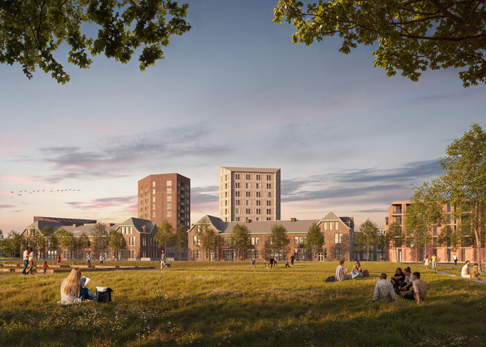 Zonsondergang bij het Kazernekwartier: op een grasveld zitten groepjes mensen gezellig samen, met nieuwbouw op de achtergrond. Op de achtergrond zijn de nieuwbouwcomplexen te zien. 